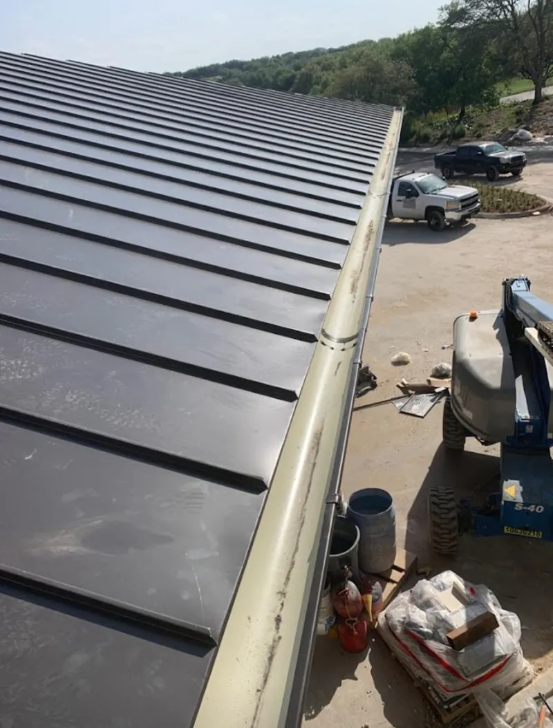 Standing seam panel and gutter detail on a metal roofing jobsite in Bedford